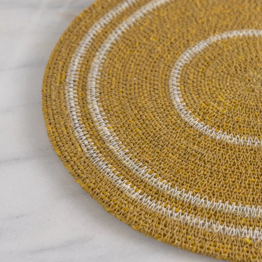 Closeup of a round woven placemat with concentric circle pattern on a marble surface