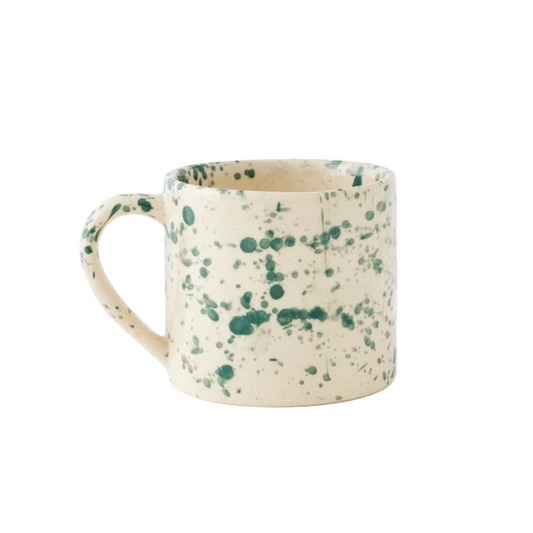A straight-sided round mug with a warm cream base and translucent forest green splattered pattern, shown against a plain white background.