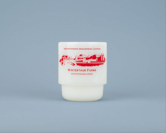 A white milk glass mug with the words 'REGISTERED HOLSTEIN CATTLE' in red above a red barn graphic with "WINTERTHUR FARMS - WINTERTHUR, DELAWARE' in red below against a blue background