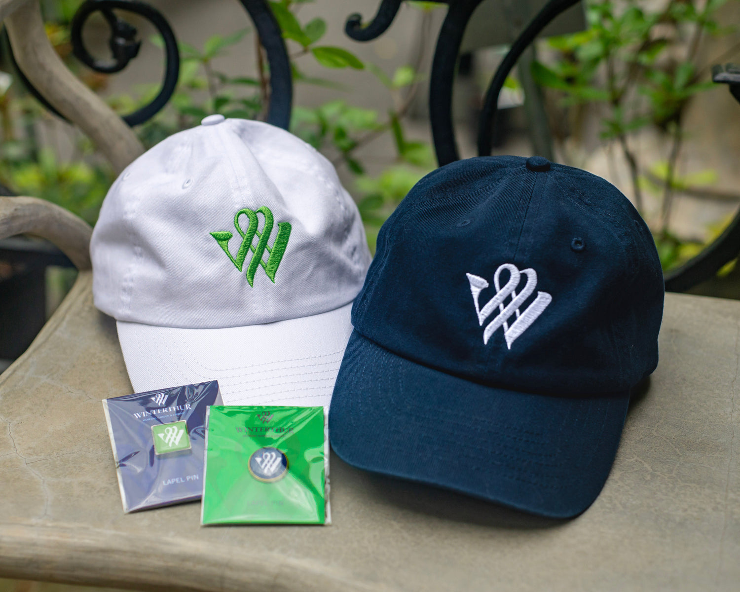 2 twill baseball hats, 1 white with our bright green "W" logo and one navy blue with our white "W" logo, and 2 lapels pins, 1 green square with white "W" logo set in silver & 1 navy circle with white "W" logo set in gold.