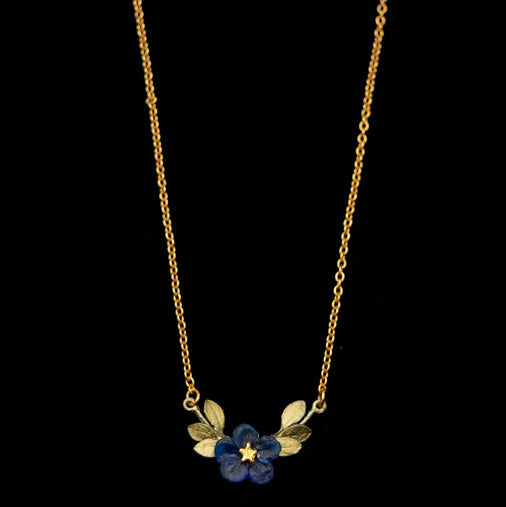 Gold necklace with a blue floral pendant on a black background