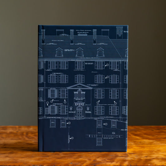 Front cover of a blue notebook with architectural blueprint design on a wooden tabletop and gray background