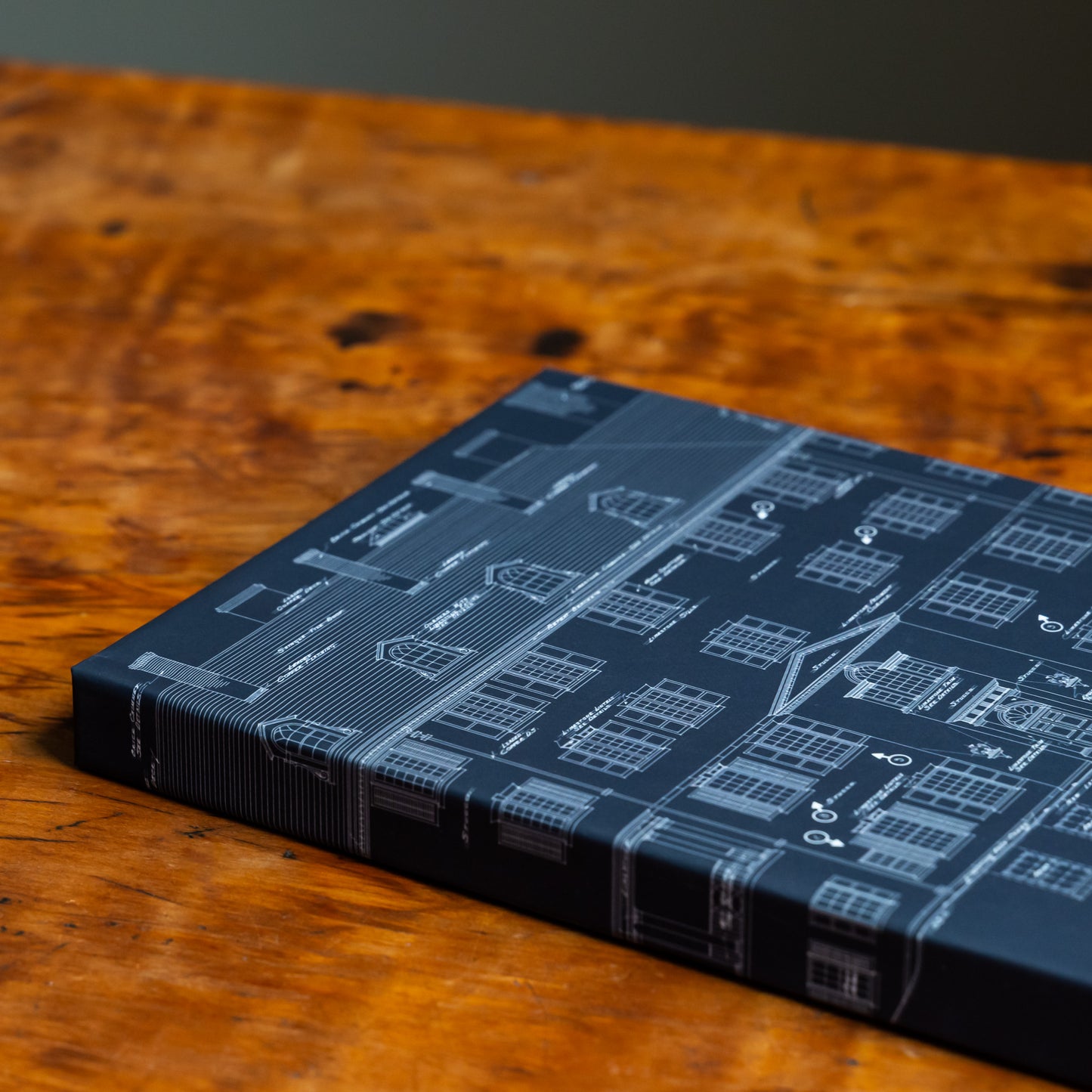 Blue notebook with an architectural design on the front cover and spine on a wood tabletop.