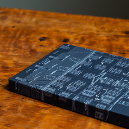 Blue notebook with an architectural design on the front cover and spine on a wood tabletop.