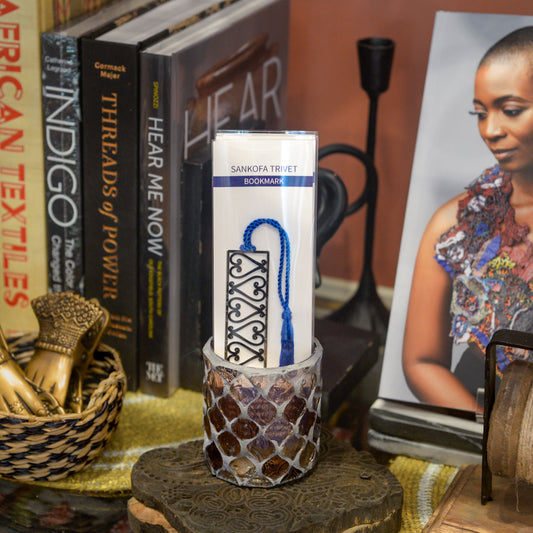 "Sankofa Trivet" bookmark on display with books and decorative objects.