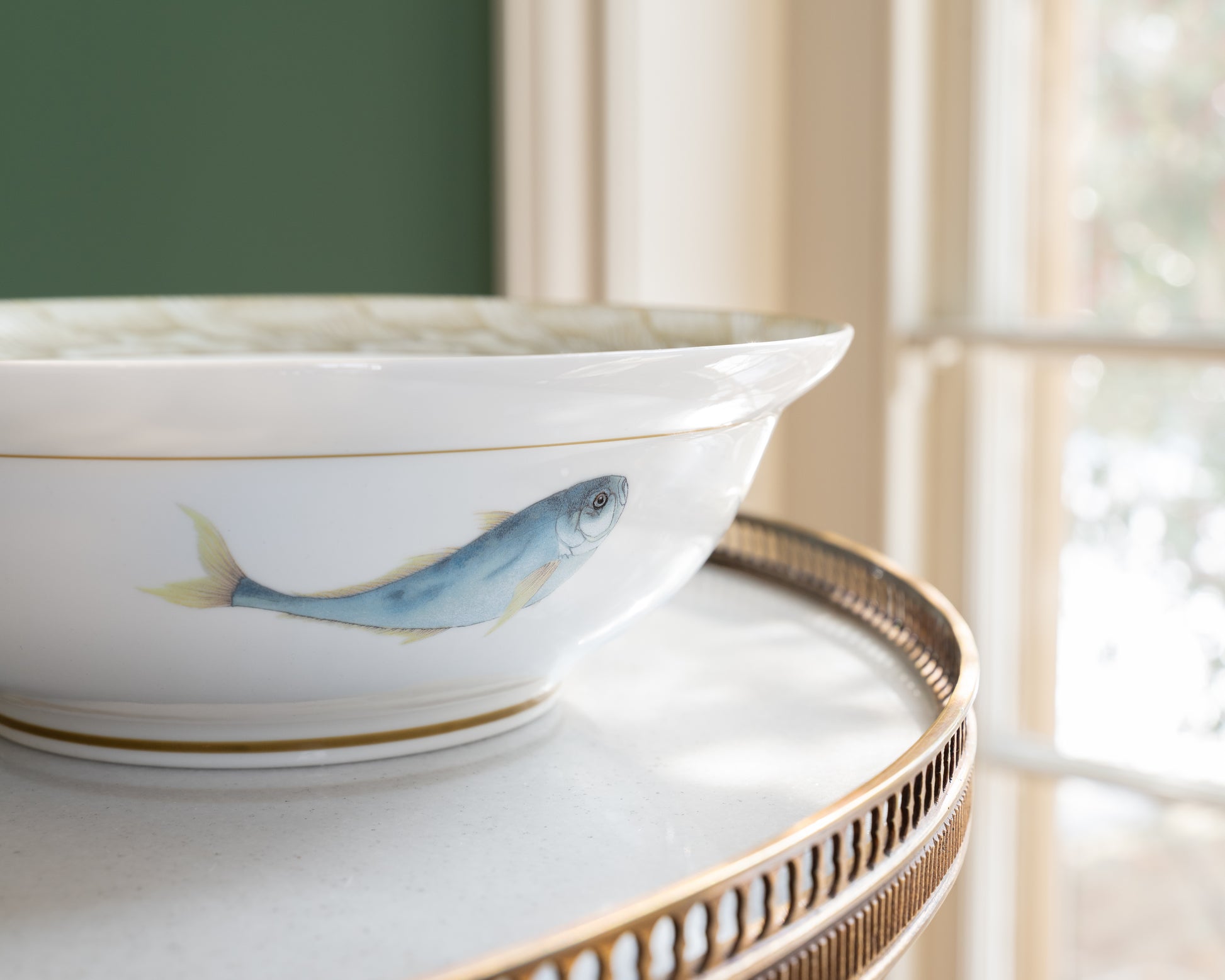 Exterior side of a white porcelain bowl with a watercolor motif of a blue trout fish