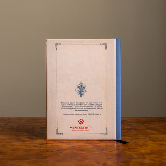 The back cover of a notebook with blue decorative elements and spine, descriptive text, and a red Winterthur logo on a wooden surface.