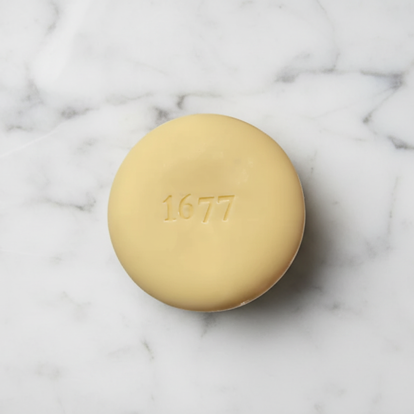 Round soap bar with '1677' stamped into it on a marble surface