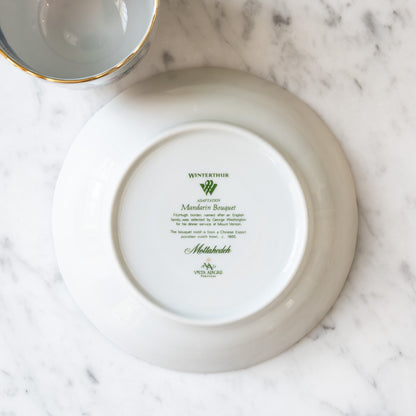 Bottom of a white ceramic saucer with branding on a marble surface. 