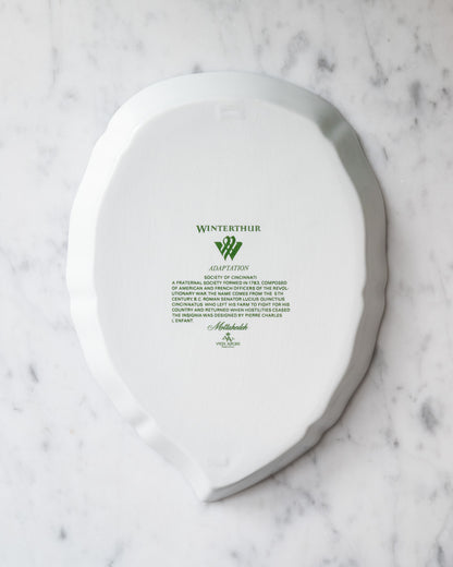 Bottom of a white porcelain leaf-shaped tray with green Winterthur logo and descriptive text