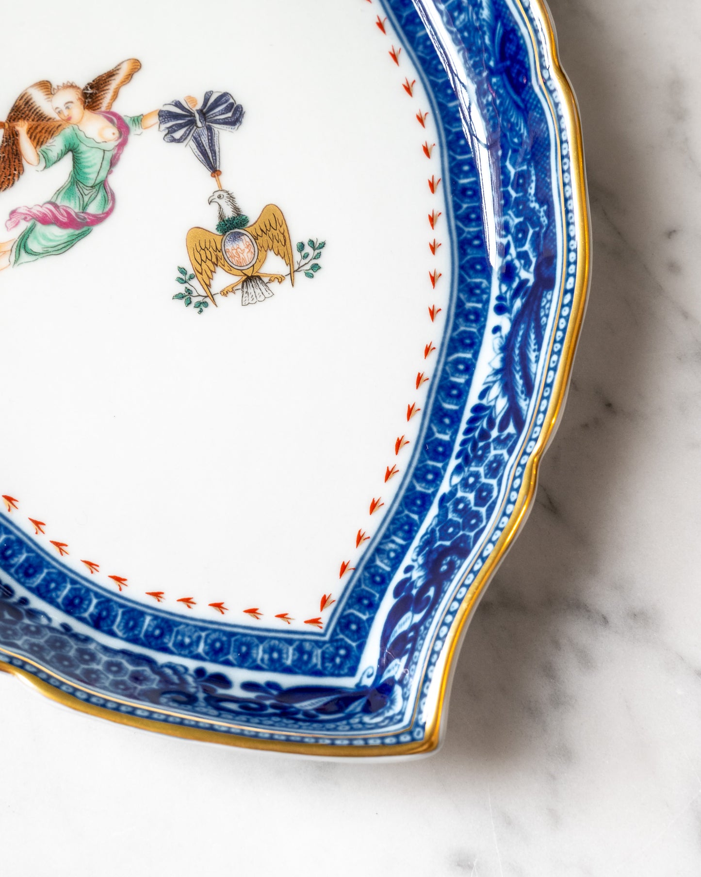 Close-up of an intricate blue and gold border of a porcelain tray on a marble surface