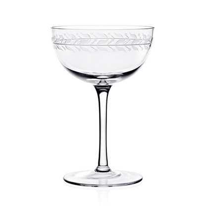 Clear crystal coup glass featuring an engraved vining leaf design around the top rim against a white background.