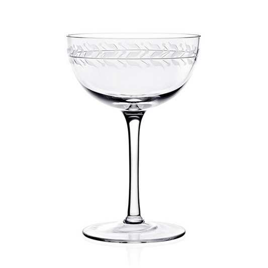 Clear crystal coup glass featuring an engraved vining leaf design around the top rim against a white background.