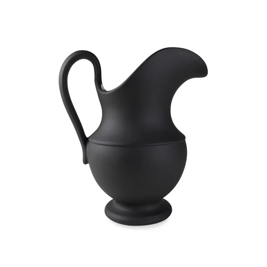 Matte black stoneware pitcher featuring a sculptural bird-like silhouette, an elegant curved handle, and a round pedestal base against a solid white background.