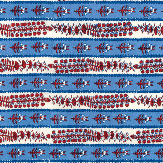 Closeup of a block-printed tablecloth with white and blue stripes decorated with red floral motifs. 
