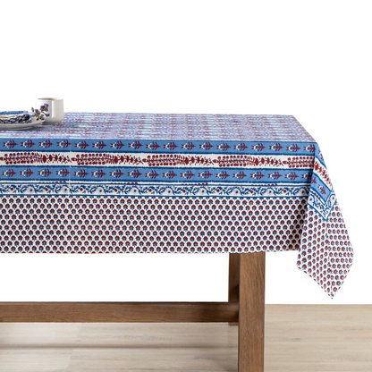 Block-printed tablecloth with white and blue stripes decorated with red floral motifs and a wide floral border draped over a wooden table with a white background