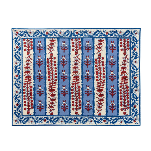 Rectangular cloth placemat with a blue and off-white striped pattern and decorated with block printed navy blue and red floral motifs laid flat against a white background