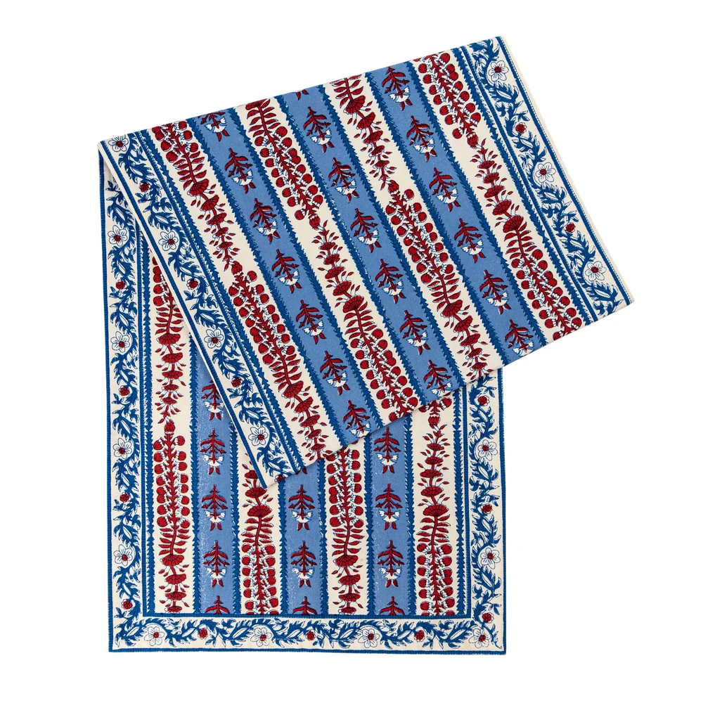 Folded table runner featuring a red, off-white and blue floral block printed design against a white background.