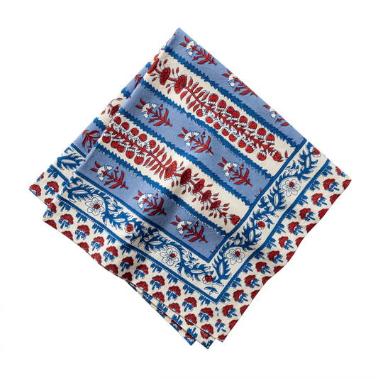 Ivory colored cloth napkin with a red and blue floral block printed design