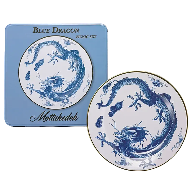 A blue and white tin picnic plate with a blue dragon illustration, shown next to its light blue square tin packaging labeled 'BLUE DRAGON PICNIC SET' and 'Mottahedeh'.