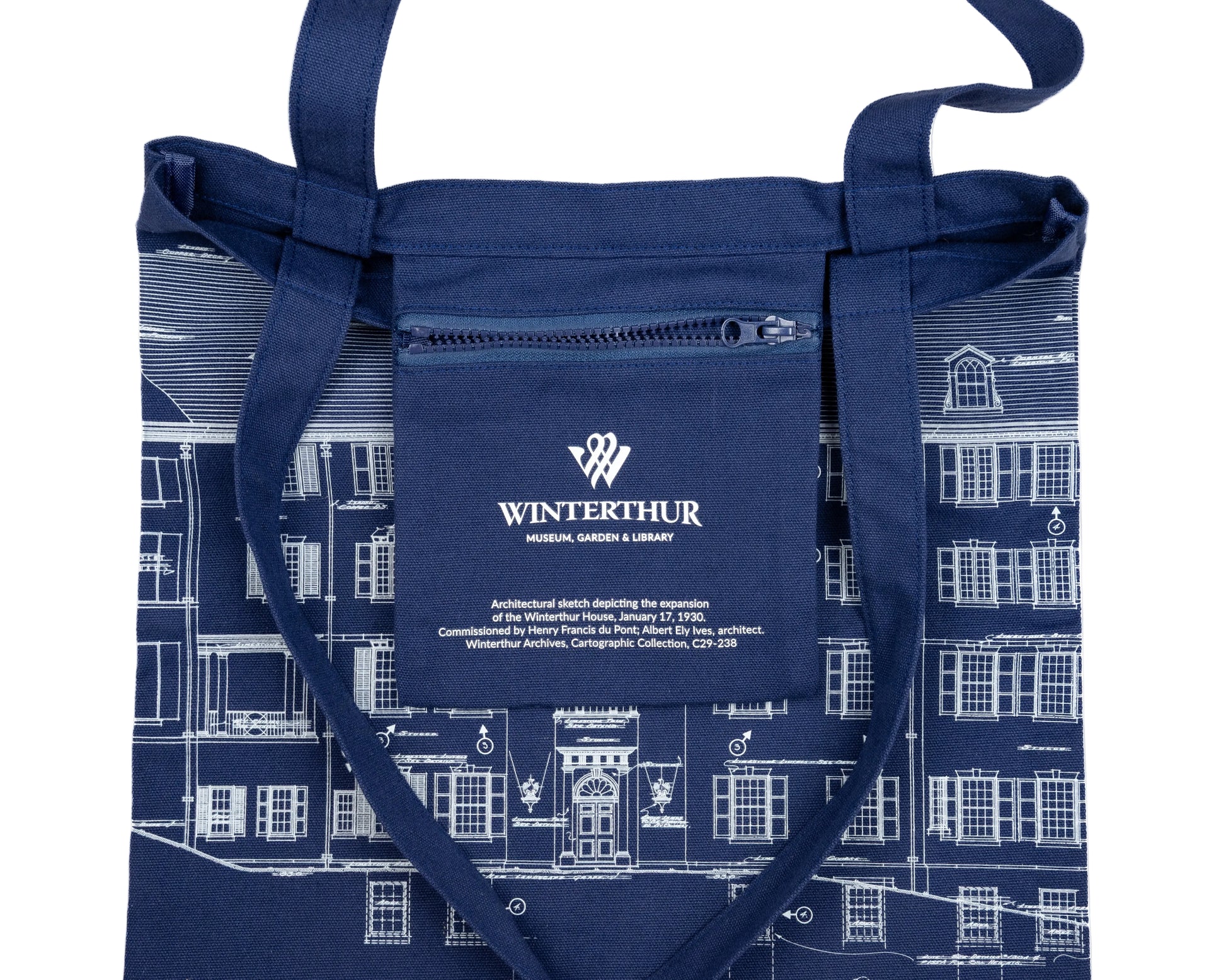 Interior zipper pocket of a navy blue tote bag with an architectural line drawing design. Pocket has the Winterthur Museum, Garden & Library logo and a description of the design.