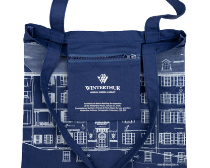 Interior zipper pocket of a navy blue tote bag with an architectural line drawing design. Pocket has the Winterthur Museum, Garden & Library logo and a description of the design.