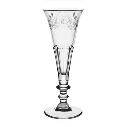 Clear crystal flute with intricate garland pattern etched on rim displayed against a white background