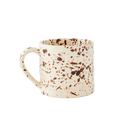 A straight-sided round mug with a warm cream base and translucent brown splattered pattern, shown against a plain white background.