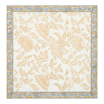 A square cream-colored cotton napkin featuring a block-printed floral pattern in a muted deep mustard and blue shown against a white background.