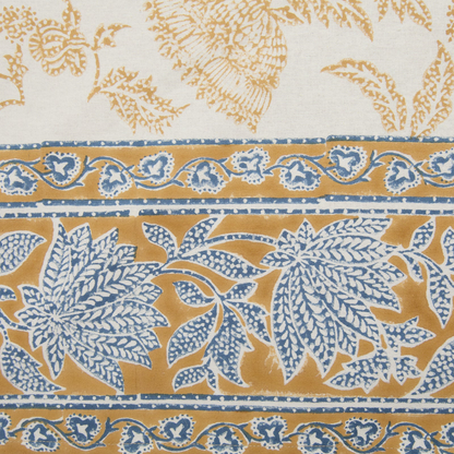 Detail of the deep mustard and blue floral printed border of a cotton tablecloth.