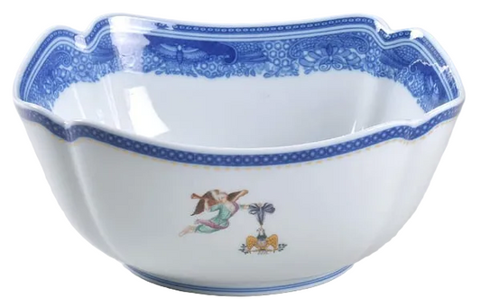 A white ceramic bowl with a scalloped rim, decorated with a blue floral pattern along the inner edge and a small hand-painted multicolor figure near the bottom.