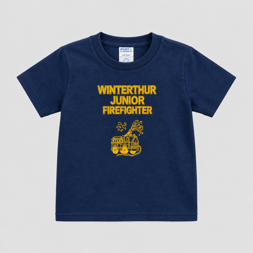 A navy blue short-sleeve t-shirt with a yellow graphic and text reading 'WINTERTHUR JUNIOR FIREFIGHTER' hanging on a black hanger against a textured wooden door.