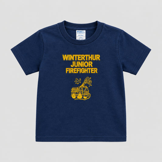 A navy blue short-sleeve t-shirt with a yellow graphic and text reading 'WINTERTHUR JUNIOR FIREFIGHTER' hanging on a black hanger against a textured wooden door.