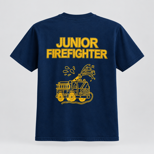 A navy blue short-sleeve t-shirt shown from the back, featuring a large yellow graphic print that reads 'JUNIOR FIREFIGHTER' above an illustration of a fire truck spraying water, set against a light gray background.