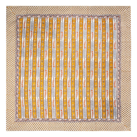 A square cotton tablecloth with a traditional Indian block printed floral pattern in orange, blue and brown.