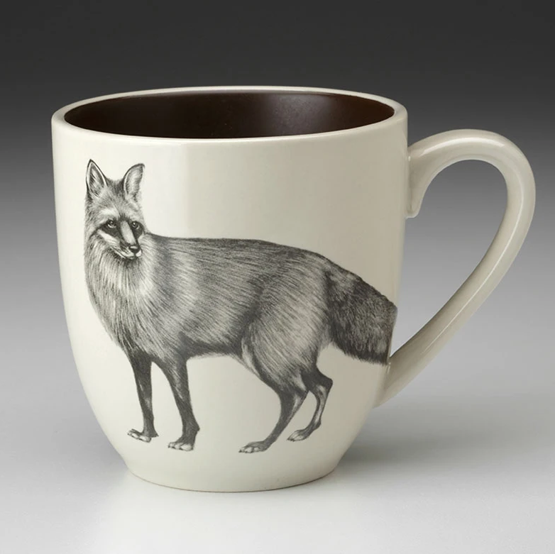 An off-white stoneware tapered mug featuring a sketch of red fox in black and  a dark brown interior.