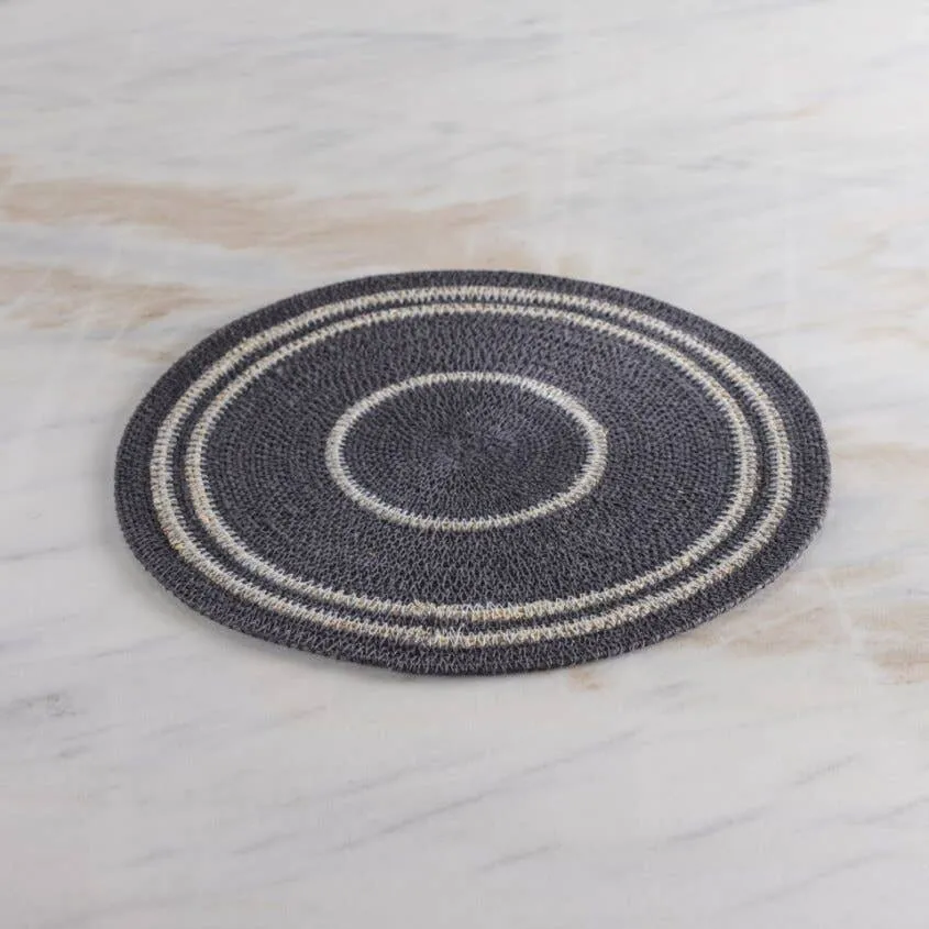 Navy blue round woven placemat with contrasting off-white bands on a marble surface