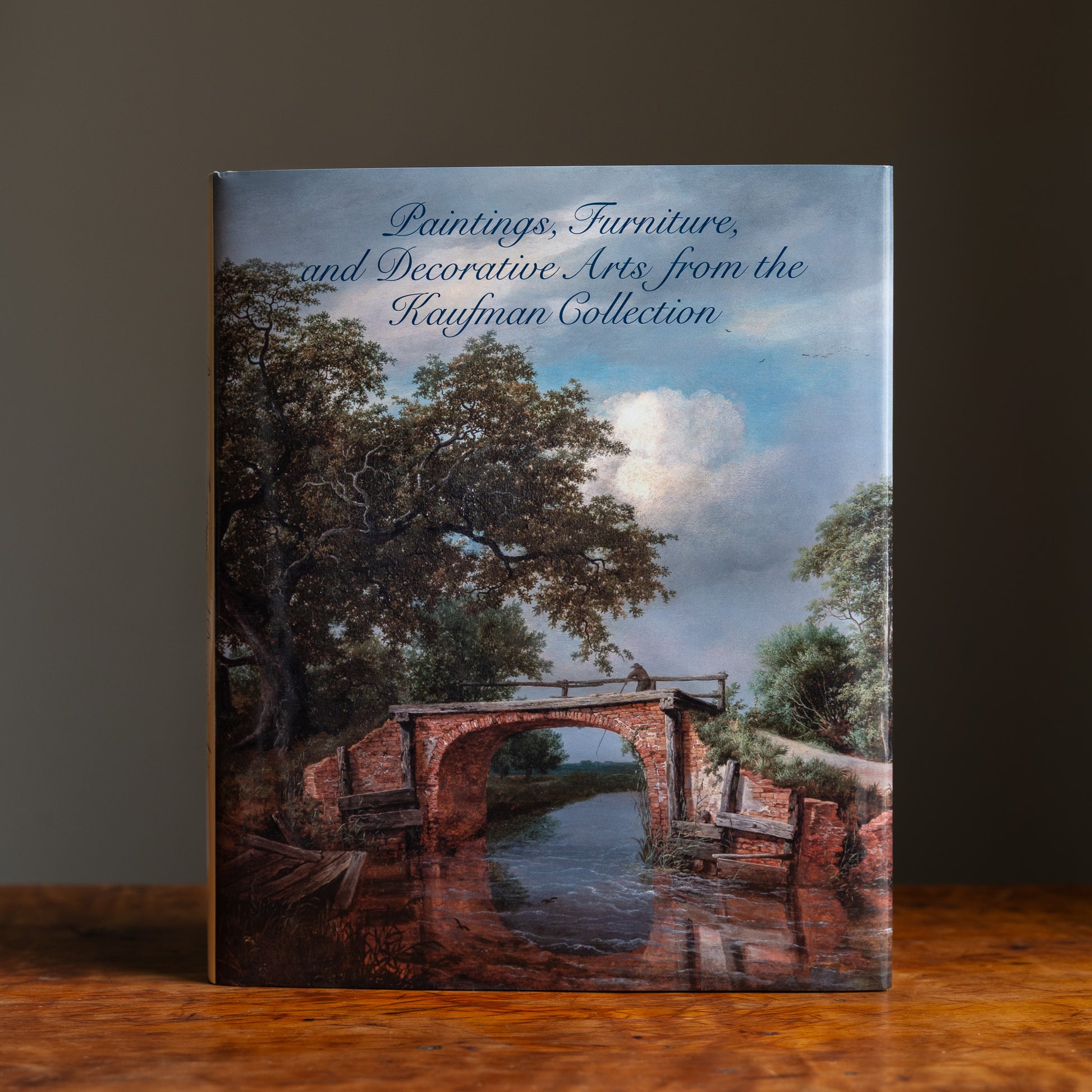 Book cover featuring the title Paintings, Furniture and Decorative Arts from the Kaufman Collection and a painting of a bridge over a river