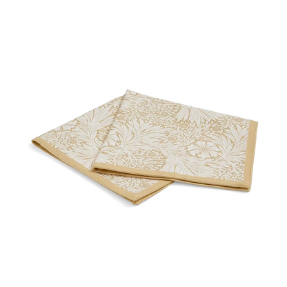 A folded napkin featuring a floral and foliage pattern in muted yellow tone, finished with a solid muted yellow border  shown against a white background.