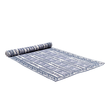 A partially rolled table runner featuring a alternating bands of light blue and white with blue floral block printed designs against a white background.