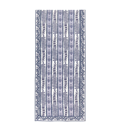 A table runner featuring a alternating bands of light blue and white with blue floral block printed designs against a white background.