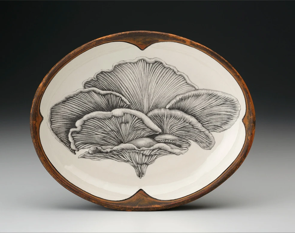 An off-white oval serving plate with a rust-brown rim featuring a sketch of a shelf mushroom in black 
