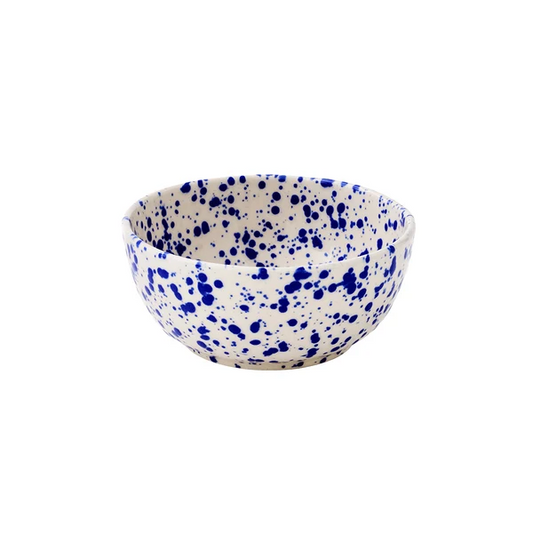 Round ceramic bowl with a cream-colored base decorated with a translucent cobalt blue splattered pattern on a white background