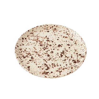 Round ceramic plate with a cream-colored base decorated with a translucent brown splattered pattern on a white background