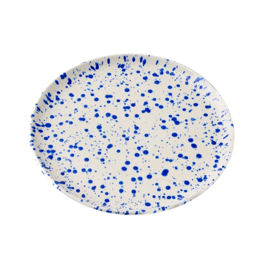 Round ceramic plate with a cream-colored base decorated with a translucent cobalt blue splattered pattern on a white background
