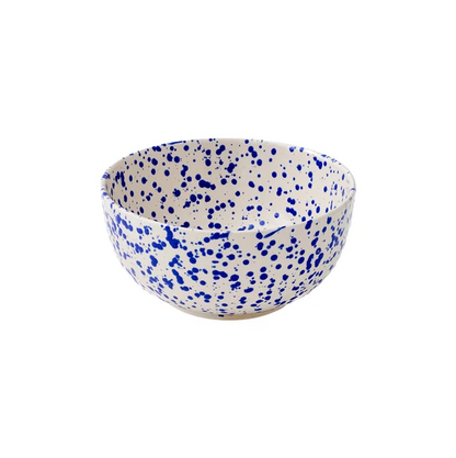 A large round ceramic bowl with a cream-colored base decorated with a translucent cobalt blue splattered pattern on a white background