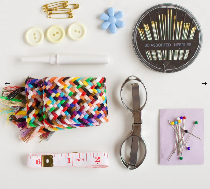 Collection of sewing and crafting tools including buttons, needles, scissors, and a measuring tape on a white background.