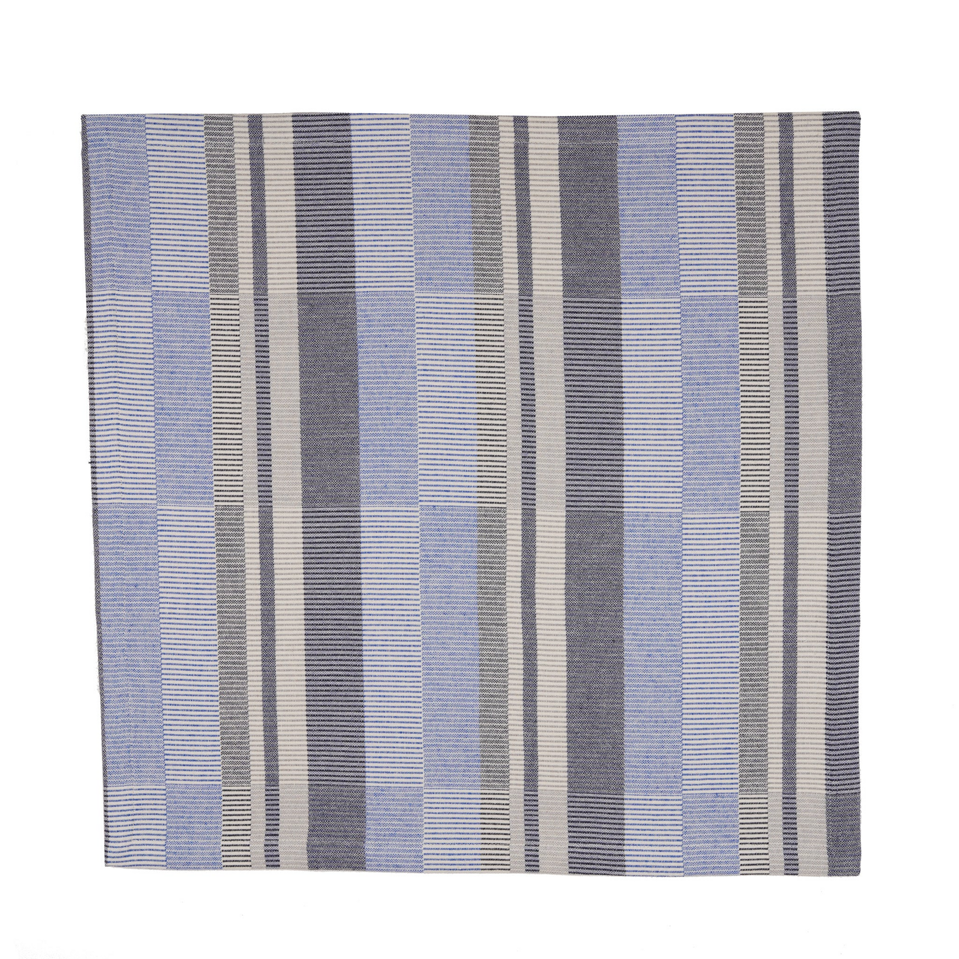 A square woven textile napkin with a striped pattern in shades of cobalt blue, navy blue, gray, and off-white, shown flat against a solid white background.